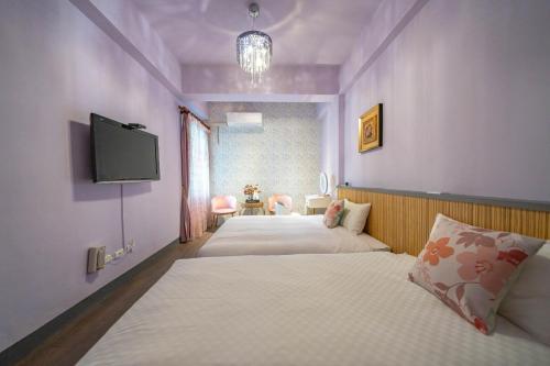 sypialnia z dwoma łóżkami i telewizorem na ścianie w obiekcie Sunny Homestay w mieście Ji’an