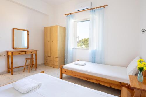 a bedroom with two beds and a mirror and a window at Alexis Apartments in Stavros