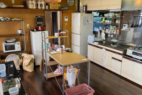 a kitchen with white appliances and a table in it at 北アルプスの麓｜一軒家のシェアハウス内の和室宿／一匹のひつじ邸 in Ō-shinden