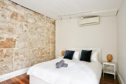 a bedroom with a white bed with a stone wall at Spacious 3 Bedroom House Darlinghurst City Centre 2 E-Bikes Included in Sydney