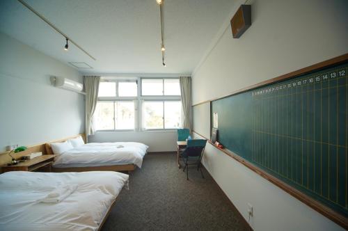 a dorm room with two beds and a chalkboard at YUKUSA OHSUMI UMI no GAKKO in Kanoya