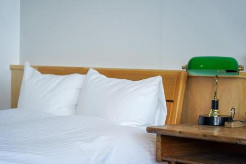 a bed with white sheets and a green lamp on a table at YUKUSA OHSUMI UMI no GAKKO in Kanoya