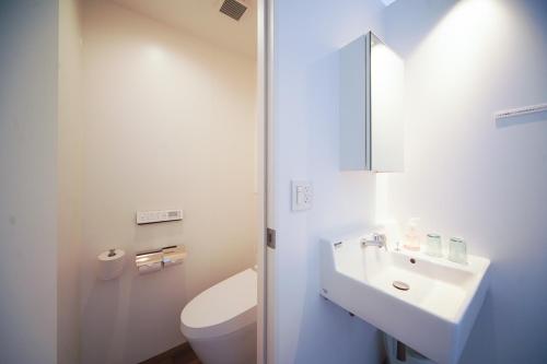 a white bathroom with a toilet and a sink at YUKUSA OHSUMI UMI no GAKKO in Kanoya