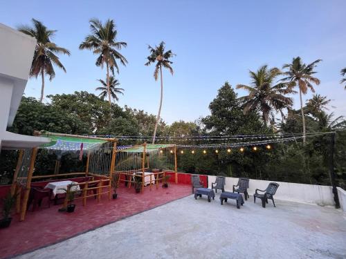 um pátio com uma mesa, cadeiras e palmeiras em Anugraha Lotus Homestay em Varkala