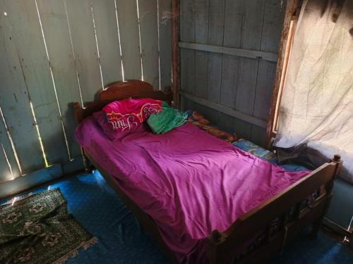 Cama pequeña con manta morada en una habitación en Omah Ngiyup, en Semarang