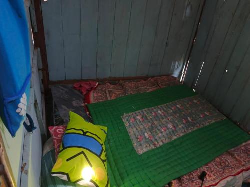 a small room with a bed with a green comforter at Omah Ngiyup in Semarang