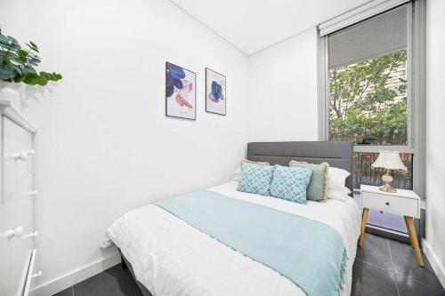 um quarto branco com uma cama e uma janela em Stay Steps from Olympic Park : Spacious 3-Bedroom em Sidney