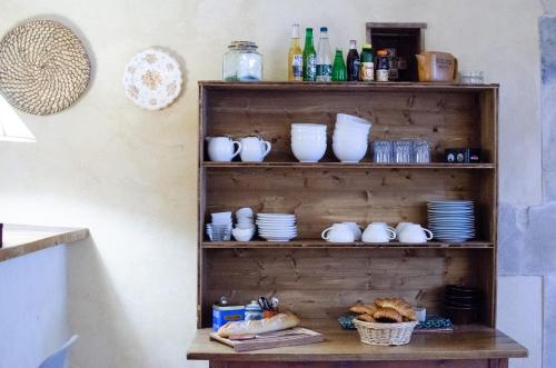 a shelf with plates and cups and dishes on it at Chambres d'hôtes - Le Mas du Colombeyras in Espeluche