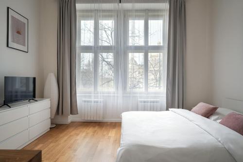 Dormitorio blanco con cama y ventana grande en Museum View Apt by SeeUPrague, en Praga