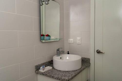 a white bathroom with a sink and a mirror at Cozy Beach House in La Romana