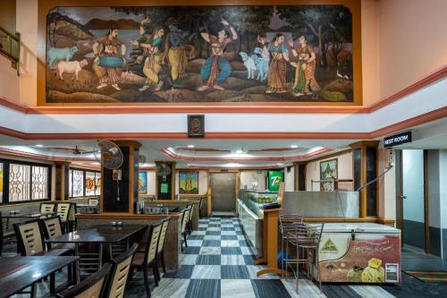 a restaurant with tables and chairs and a painting on the wall at Sree Bharani Hotels in Tirunelveli