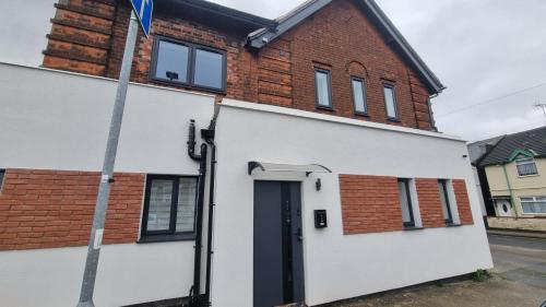 a white house with a black door and a brick building at Glamour no2 Flat in Mansfield