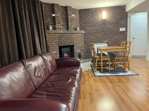 a living room with a leather couch and a table and a fireplace at Entire Basement Apartment in Mississauga, Etobicoke in Mississauga