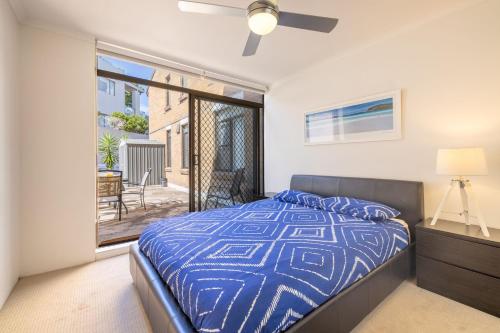 a bedroom with a bed with a blue comforter at Fleetwood 3 63 Shoal Bay Road Relaxed living with water views overlooking Shoal Bay in Shoal Bay