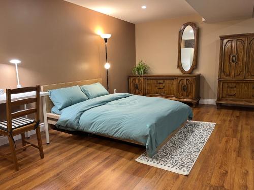 1 dormitorio con cama, silla y espejo en Entire Basement Apartment in Mississauga, Etobicoke, en Mississauga