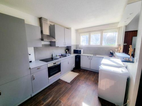 a kitchen with white cabinets and a wooden floor at Duplex à 2 pas de l'aéroport, proche ONU & Palexpo in Ferney-Voltaire