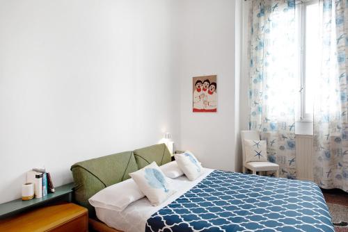 Schlafzimmer mit einem blauen und weißen Bett und einem Fenster in der Unterkunft Casa Olimpia in Savona