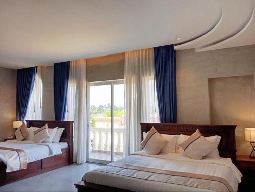 a bedroom with two beds and a large window at Sokchea Kampot Hotel in Kampot