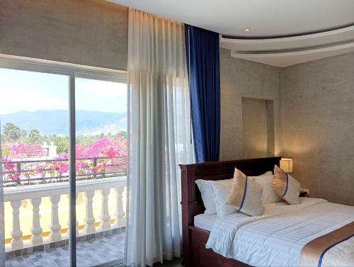 a bedroom with a bed and a large window at Sokchea Kampot Hotel in Kampot
