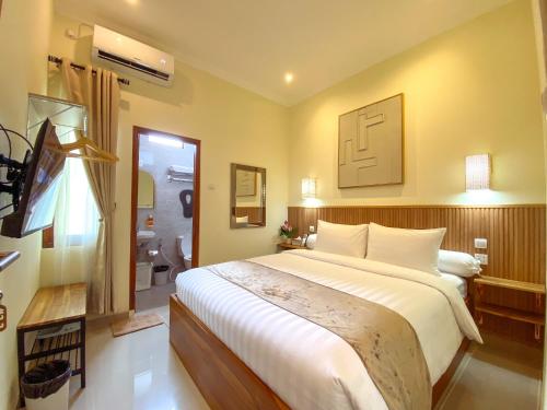 a bedroom with a large bed and a bathroom at Siji Nayan Vacation Home in Yogyakarta