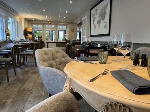 a restaurant with a wooden table with wine glasses at Hôtel Restaurant La Maison in Trébeurden