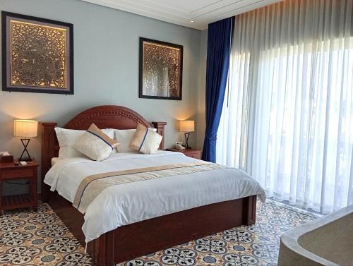 a bedroom with a bed and a large window at Sokchea Kampot Hotel in Kampot
