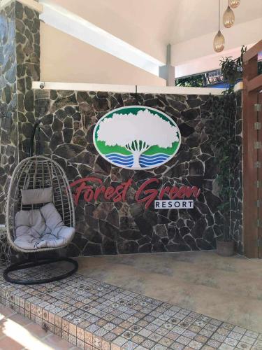 a rock wall with a sign and two chairs at Forest green resort in Lipa