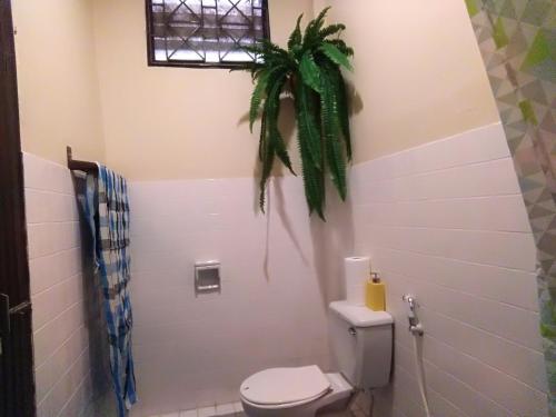 a bathroom with a toilet and a plant on the wall at Goodnighthostel@Trang in Trang