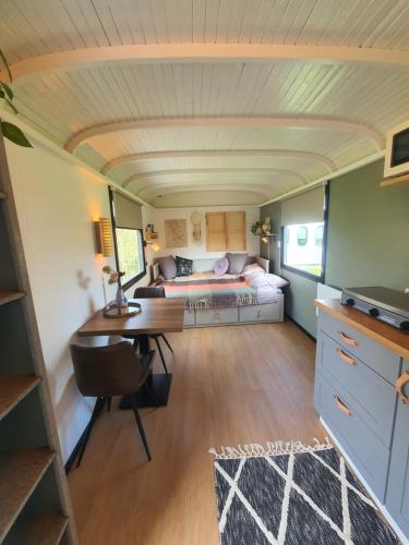 een woonkamer met een bed en een bureau in een kamer bij Pipowagen het Sleephuis in Rohel