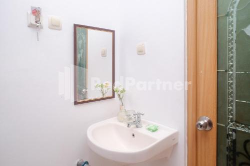 Un baño con un lavabo blanco y un espejo. en Ndalem Pundhi Maguwoharjo RedPartner, en Seturan