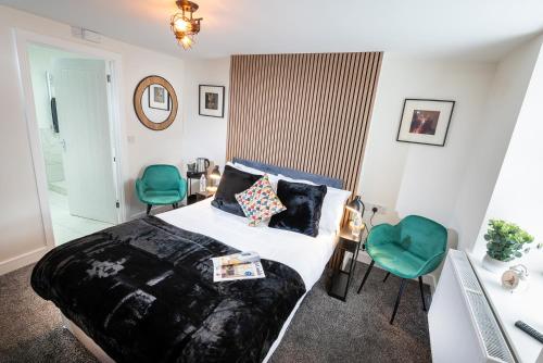 um quarto com uma cama e 2 cadeiras verdes em Kings Arms Suites - Luxury Double - Freestanding Bath - Self Check In em Whitehaven