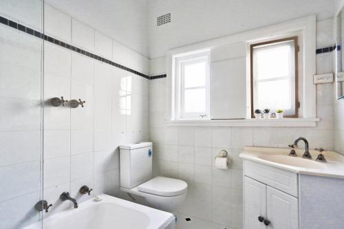 a white bathroom with a toilet and a sink at Spacious 3 Bedroom on the edge of Downtown Herford St 2 E-Bikes Included in Sydney
