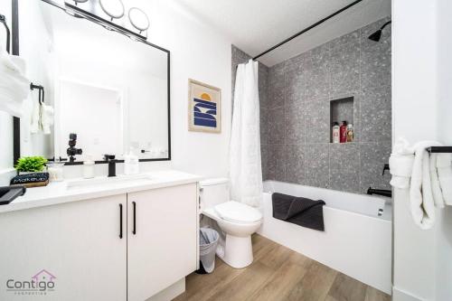 a bathroom with a sink and a toilet and a bath tub at Urban Zen, AirCon, King Bed, 10 min WEM & DT! in Edmonton