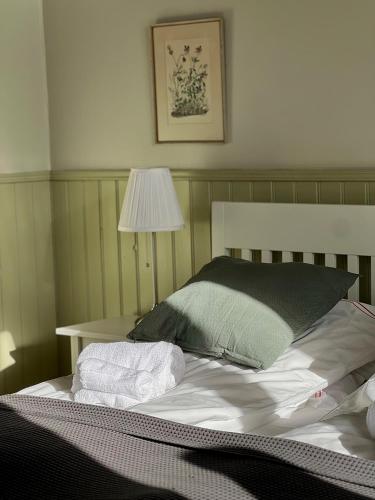 a bed with two towels on it with a lamp at Svabesholms Kungsgårds B&B och Pensionat Stenshuvud in Kivik