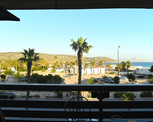 a view of a parking lot with palm trees and the ocean at Seaside Bliss in Varkiza - Dreamy Balcony with Stunning Sea Views in Varkiza