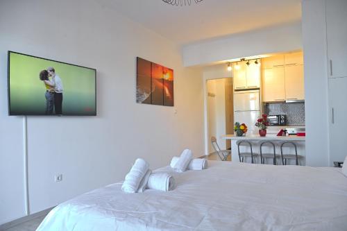 a bedroom with a large white bed with a tv on the wall at Seaside Bliss in Varkiza - Dreamy Balcony with Stunning Sea Views in Varkiza
