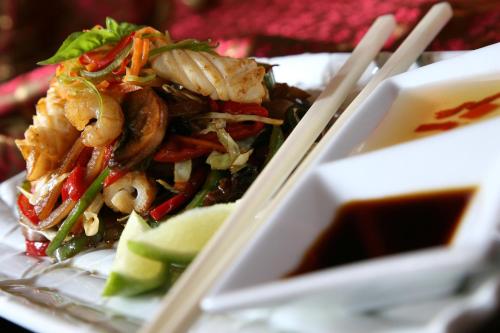 a plate of food with shrimp and vegetables and chopsticks at Les Jardins De La Koutoubia in Marrakech