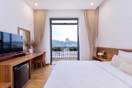 sypialnia z łóżkiem i telewizorem oraz balkonem w obiekcie The Elegant Dalat w mieście Da Lat
