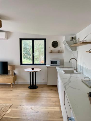 une cuisine blanche avec une table et une fenêtre dans l'établissement Caseddu 100m de la plage, à Belvédère