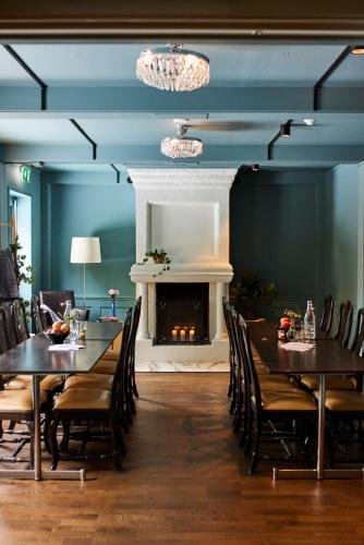 a dining room with two tables and a fireplace at Home Hotel Smedjan in Sandviken