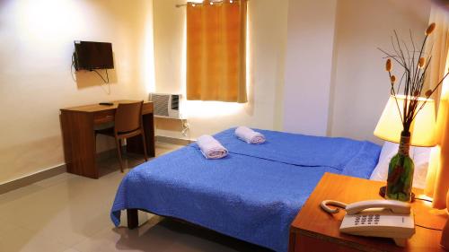 a bedroom with a bed with a phone and a desk at CounTess Pension House in Liloan