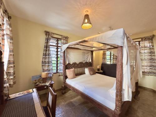 een slaapkamer met een hemelbed en ramen bij Villa Twiga in Ukunda