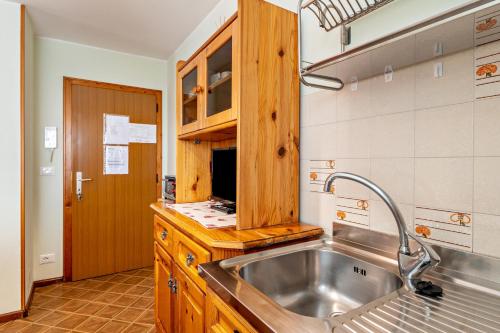 a kitchen with a stainless steel sink and wooden cabinets at Appartamento Aurone in Arabba