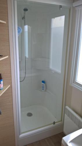 une douche avec une porte vitrée dans une salle de bain dans l'établissement location mobile-home IRM super octavia 36m2, à La Tranche-sur-Mer