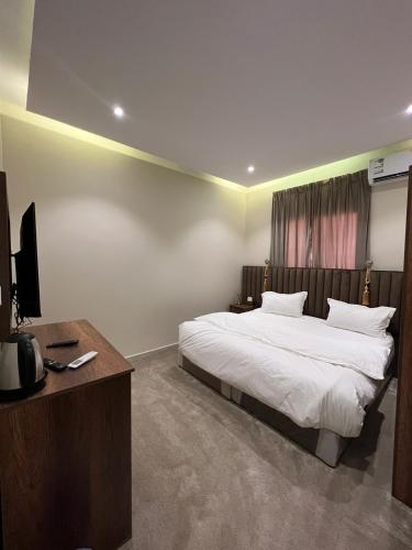 a bedroom with a bed and a desk with a television at السلطان للشقق المفروشة in AlUla