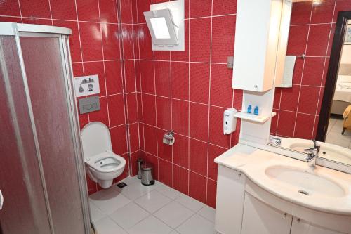 baño de azulejos rojos con aseo y lavamanos en Melis Pansiyon en Bodrum