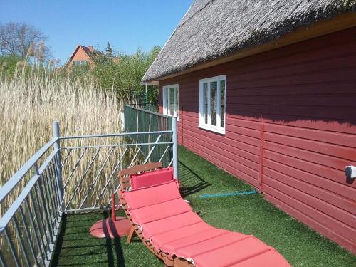 a red building with a bench on the side of it at Striking Holiday Home in Sternberg with Jetty in Sternberg