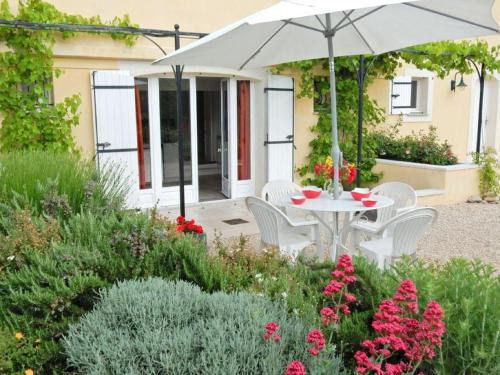 a patio with a table and chairs and an umbrella at Apartment in Montbrun les Bains near forest in Reilhanette