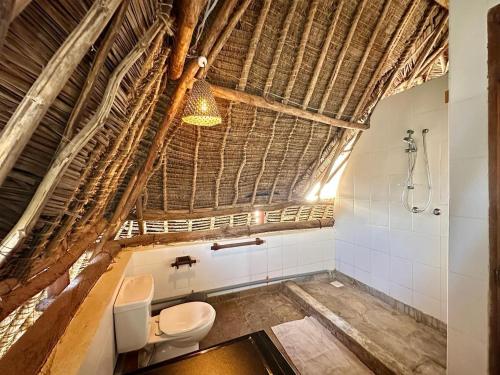 an attic bathroom with a toilet and a shower at Villa Twiga in Ukunda