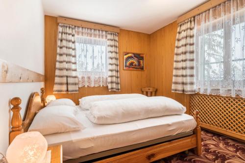 een bed in een slaapkamer met houten wanden en ramen bij Samont Appartment 7 in Arabba